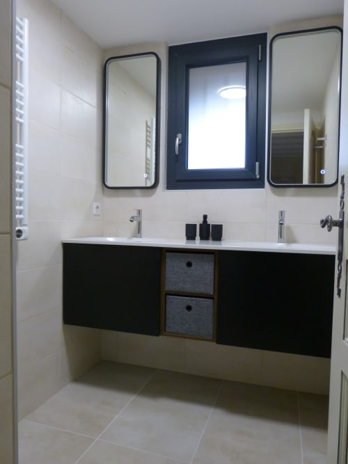 Modern bathroom in Cérise room at Villa Thébaïde with dual sinks, black vanity, and framed mirrors
