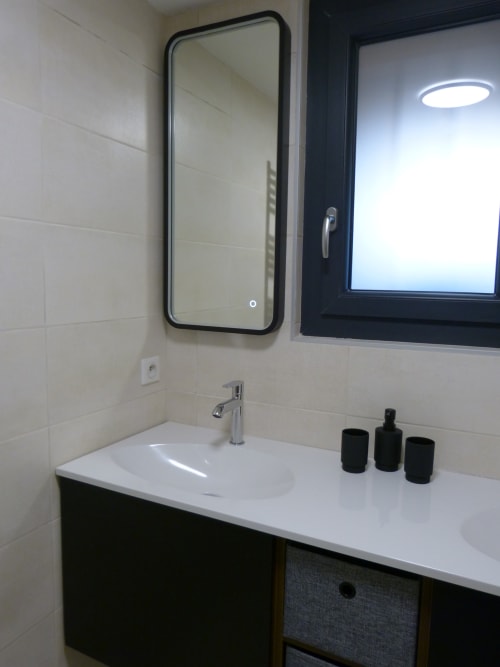 Modern bathroom at Villa Thébaïde with white sink, black framed mirror, and chrome faucet in Cérise room