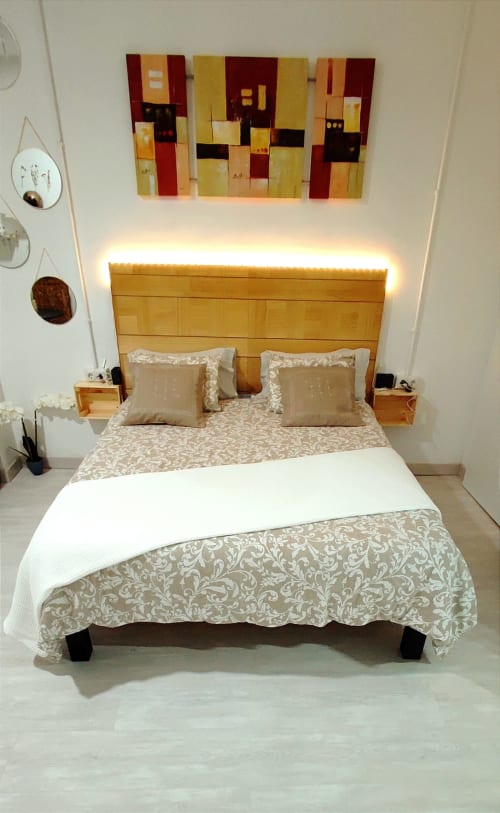 Dormitorio moderno en Apartamentos Huelintown en Málaga con cama de madera, iluminación cálida y arte abstracto en la pared