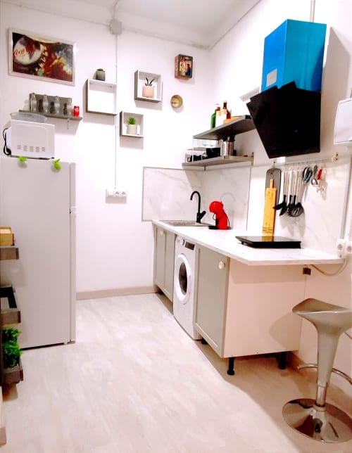 Kitchenette compacta en Apartamentos Huelintown Málaga con electrodomésticos blancos, fregadero, lavadora y equipamiento empotrado