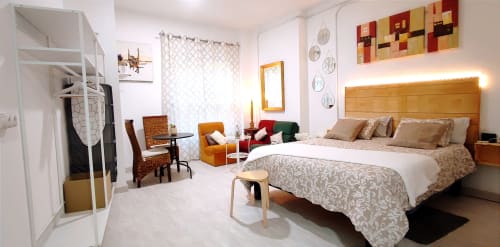 Amplio dormitorio moderno en Apartamentos Huelintown, Málaga, con cama de madera, vistas a la ciudad, TV y mobiliario contemporáneo