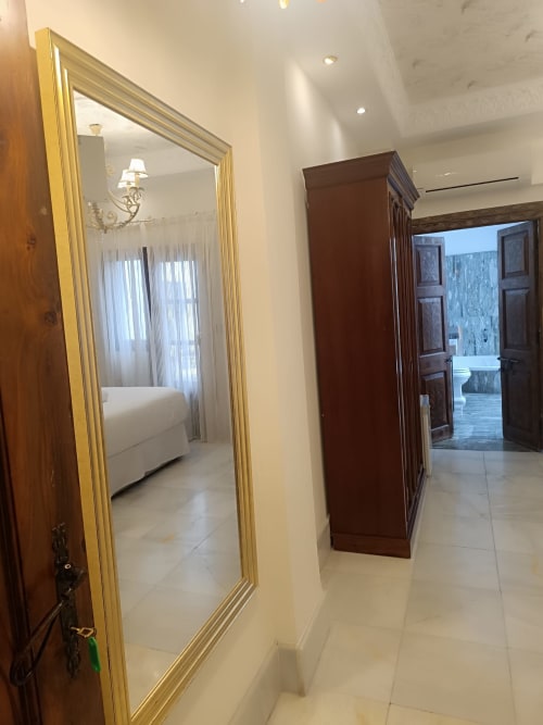 Pasillo de la Suite Comares Granada con espejo de marco dorado y armario de madera oscura