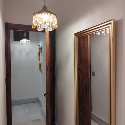 Pasillo del hotel en Suite Comares Granada con lámpara de cristal colgante y marcos de puerta de madera
