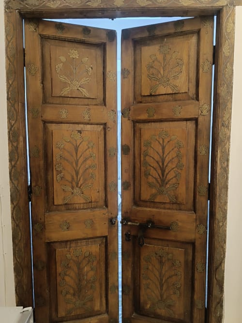 Puertas dobles de madera ornamental con paneles florales tallados a mano en el hotel Suite Comares de Granada