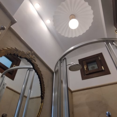 Baño moderno en el hotel Suite Comares de Granada con zona de ducha y iluminación de techo