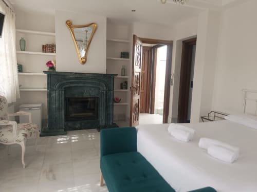 Habitación del hotel Suite Comares en Granada con chimenea, cama, muebles turquesas y estantería blanca con decoración