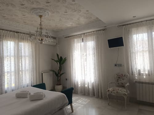 Habitación luminosa del hotel Suite Comares en Granada con cama, muebles elegantes e iluminación natural desde amplias ventanas