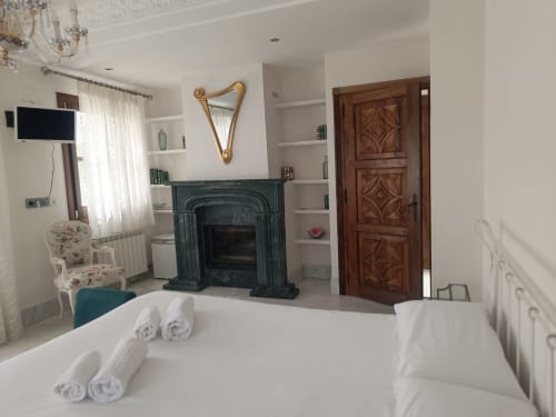 Lujosa Suite Comares en Granada con chimenea, puerta de madera, ropa de cama blanca y decoración clásica