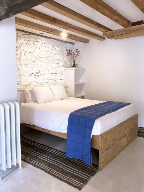Dormitorio rústico en Casa rural MAÑARINEGI con vigas de madera, pared de ladrillo blanco, manta azul y mobiliario tradicional