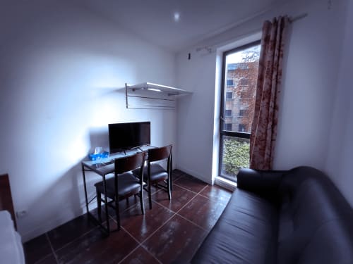 Chambre moderne avec bureau, TV, canapé et balcon vitré vue sur Montreuil