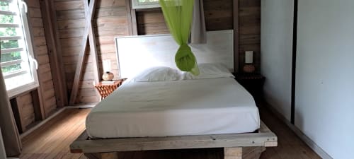 Bright bungalow bedroom at Le Bougainvillier Blanc with white bed, wooden beams, green curtain, and sea view doors in Pointe