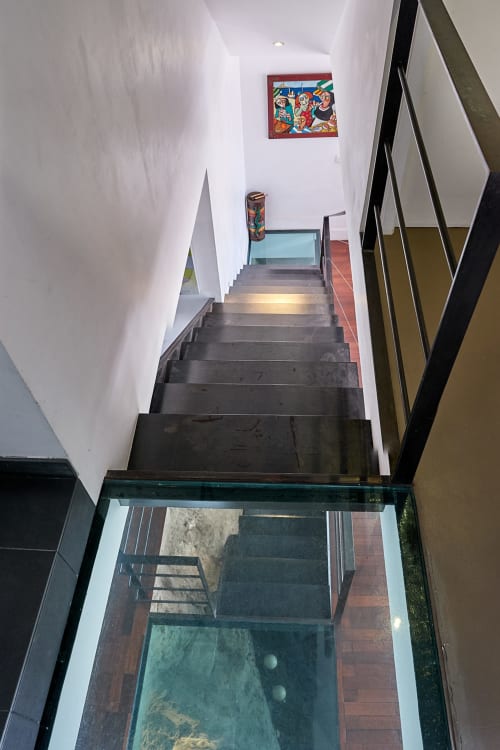 Escalier étroit de la maison d'hôtes La Luna Marseille aux murs blancs, marches noires et œuvres d'art colorées à l'étage supérieur
