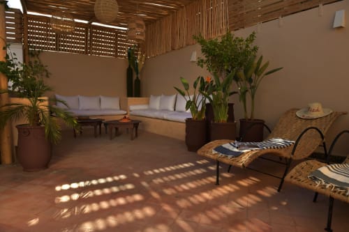 Sunny courtyard at Riad Palau Marrakech with cushioned seating, potted plants, and wicker loungers