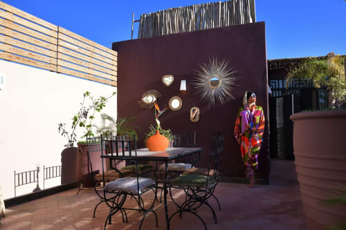 Riad Palau Marrakech courtyard with decorative dark wall, dining table, potted plants, and guest in colorful attire