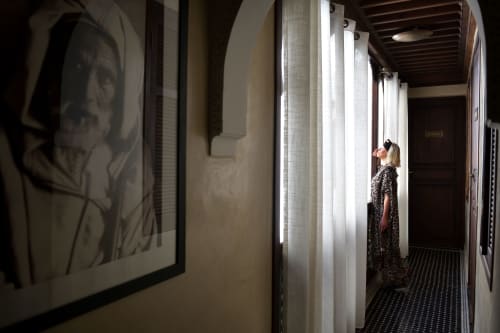 Guest in hallway of Riad Palau Marrakech with portrait artwork and atmospheric lighting in Marrakesh riad.