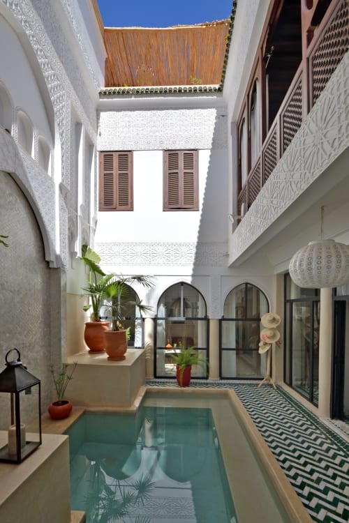 Riad Palau Marrakech courtyard with turquoise pool, arched doors, potted plants, and white Moroccan architecture, Marrakesh