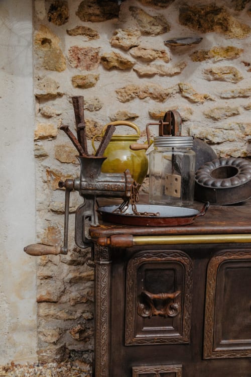 Cuisine rustique vintage du BnB Le Clos du Buisson avec poêle ancien, bouilloire jaune et murs en pierre