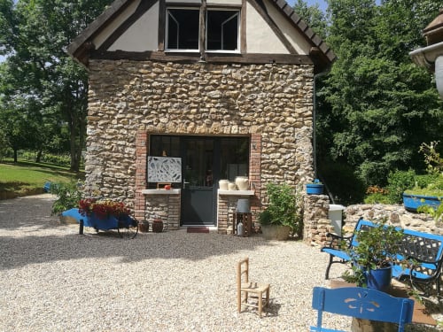 Façade de cottage en pierre du Clos du Buisson à Saint Aubin sur Gaillon, avec mobilier bleu et cour gravillonnée