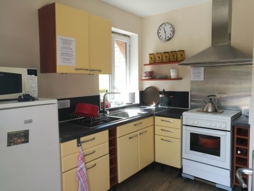 Cuisine jaune avec plans de travail noirs et appareils en inox au Clos du Buisson, Saint Aubin sur Gaillon
