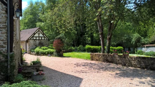 La cour du Clos du Buisson BnB à Saint Aubin sur Gaillon avec allée en gravier, bâtisses en pierre et jardins luxuriants