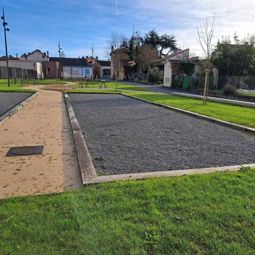 Terrain de boules aux Deux Porches avec surfaces en sable et graviers, gazon verdoyant et bâtiments historiques à Verrières