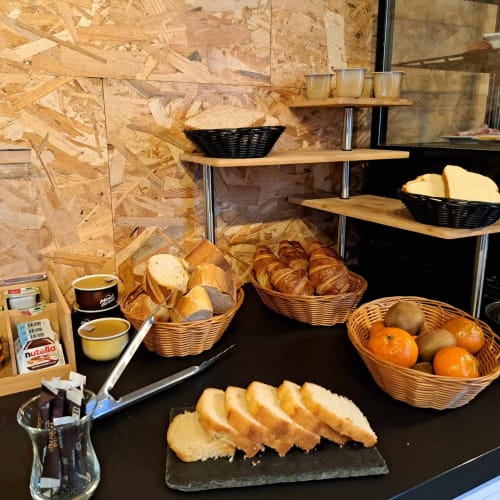Présentation du petit-déjeuner à Les Deux Porches avec viennoiseries fraîches, croissants, pain et fruits frais dans des paniers en osier