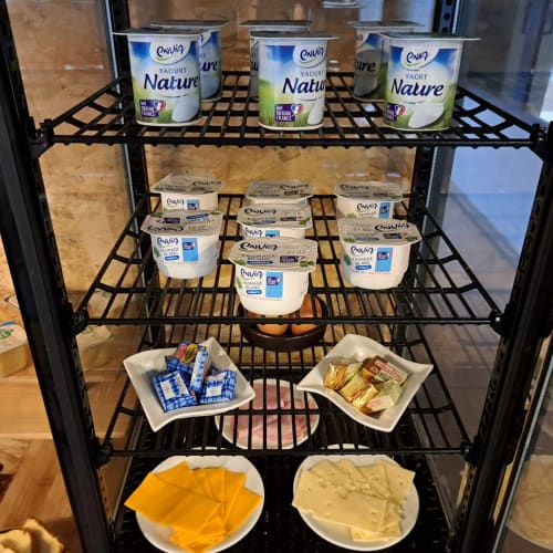 Produits laitiers et condiments exposés dans un rayon réfrigéré à l'espace petit-déjeuner de l'hôtel Les Deux Porches à Verrières