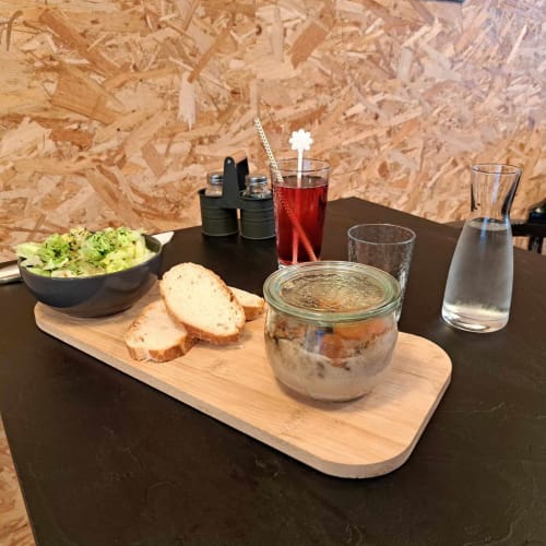 Table gastronomique aux Deux Porches : pain, pâté, salade et boissons devant un mur de liège
