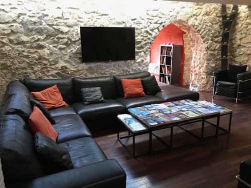 Salon moderne de La Luna Marseille B&B avec canapé en cuir noir, murs en pierre et espace divertissement