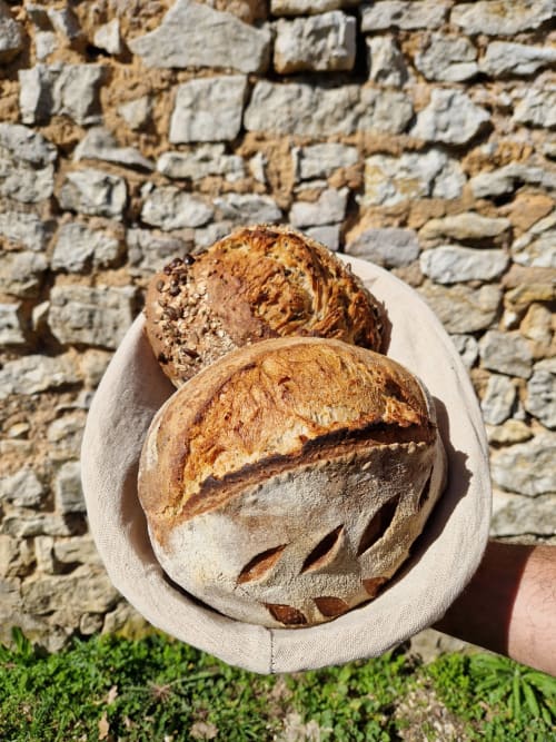 Pain artisanal fraîchement cuit dans un linge lin devant un mur de pierre à Maisonaurinko B&B, Thenon