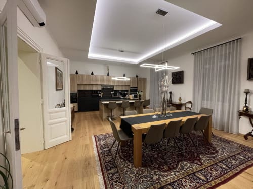 Sala da pranzo e cucina open-plan moderna dell'hotel Saint Michel a Gorizia con tavolo in legno, banconi neri e design contemporaneo
