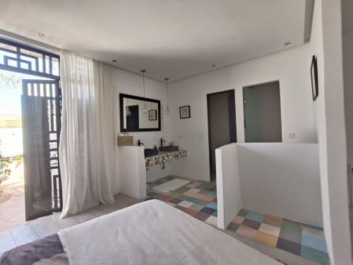Ruime slaapkamer met eigen badkamer in Riad Palau Marrakech, gekleurde tegelsvloer en moderne voorzieningen