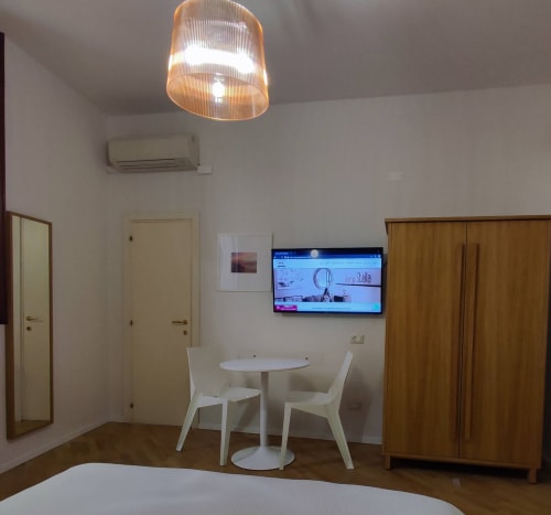 Modern hotel room at Stella CasaBono Sulmona with white dining table, flat-screen TV, wood wardrobe, and pendant lighting