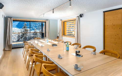 Modern meeting room at Le Chalet Mont-Blanc with mountain views, wooden chairs, and conference table in Chamonix.