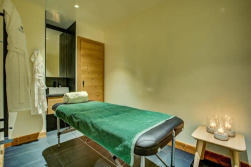 Spa treatment room at Le Chalet Mont-Blanc in Chamonix with massage bed, green towel, and candles