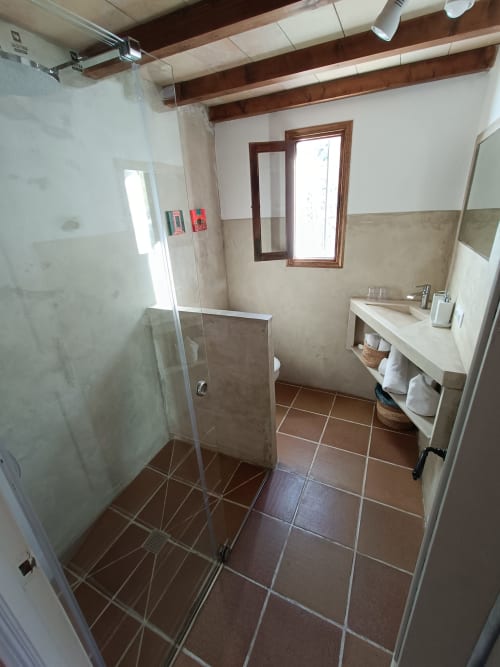 Baño moderno del Petit Hotel Sa Plana en Estellencs con ducha de acceso libre, lavamanos y techo con vigas de madera