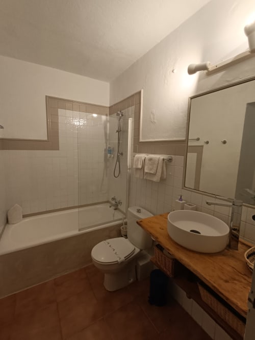 Baño moderno con lavabo blanco, inodoro, bañera con ducha y tocador de madera en Petit Hotel Sa Plana, Estellencs