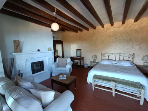 Habitación Mestral Superior en Petit Hotel Sa Plana con cama, chimenea y vistas al mar desde Estellencs