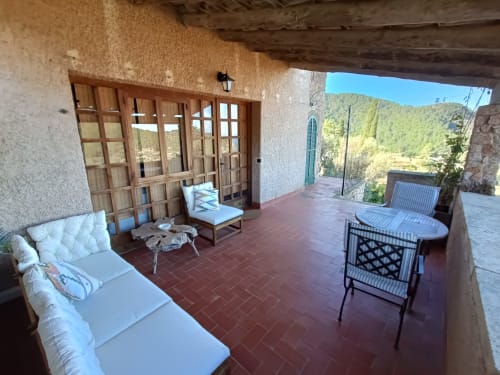 Terraza de la habitación Mestral del Petit Hotel Sa Plana en Estellencs con tumbonas y vistas a la montaña