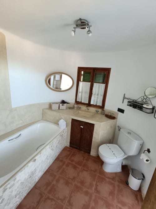 Baño Mestral del Petit Hotel Sa Plana con bañera, lavabo doble, inodoro y ventana con vistas al mar en Estellencs