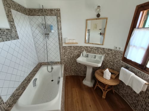 Baño con bañera, lavabo de pedestal y detalles de azulejos mosaicos en Petit Hotel Sa Plana de Estellencs