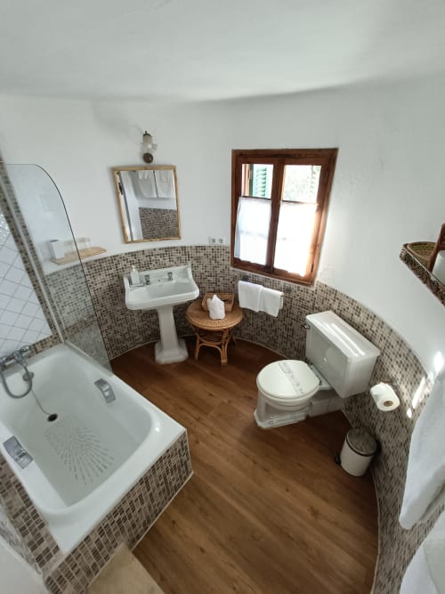 Baño de la habitación Tramuntana en Petit Hotel Sa Plana, Estellencs, con paredes de azulejos de mosaico, suelos de madera, bañera y