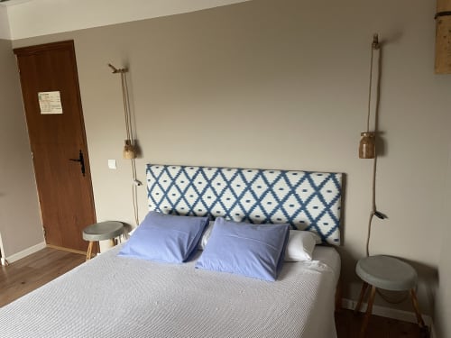 Acogedor dormitorio en el Petit Hotel Sa Plana de Estellencs con cabecero azul estampado, almohadas azules y puerta de madera rústica