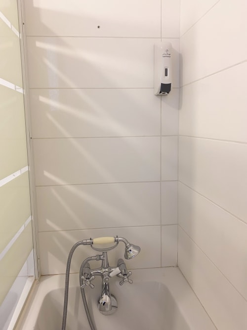 Salle de bain impeccable à l'hôtel Chambre Pasteur à Montreuil avec carrelage blanc, robinetterie vintage et distributeur de savon