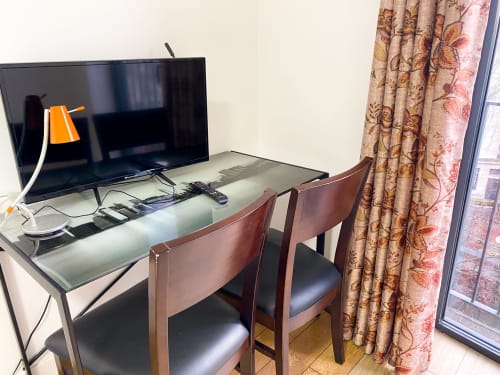 Bureau avec télévision et chaise dans la chambre de l'hôtel Chambre Pasteur, Montreuil