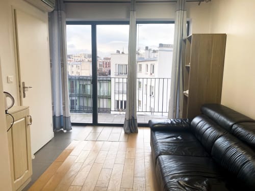 Chambre moderne à l'hôtel Pasteur à Montreuil avec canapé cuir noir, balcon vue ville et design contemporain