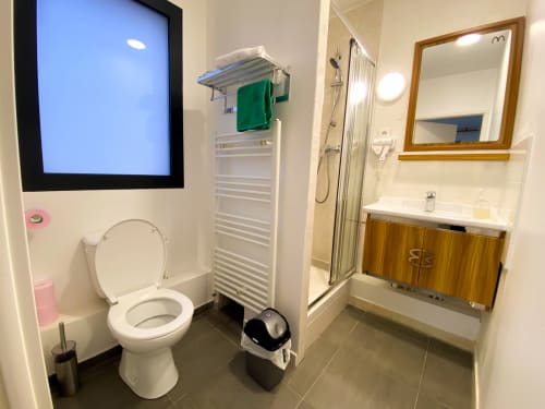 Salle de bain moderne à l'hôtel Chambre Pasteur à Montreuil avec toilettes, lavabo, douche et sèche-serviettes électrique