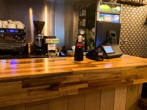 Bar à café de l'hôtel Chambre Pasteur à Montreuil avec machine à espresso, moulin et terminal de paiement sur comptoir en bois