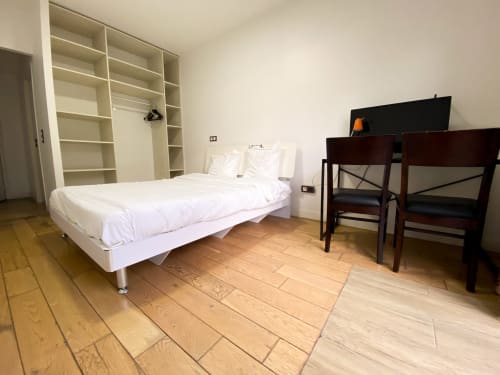 Chambre spacieuse à l'hôtel Chambre Pasteur à Montreuil avec lit blanc, parquet, espace bureau et armoire intégrée