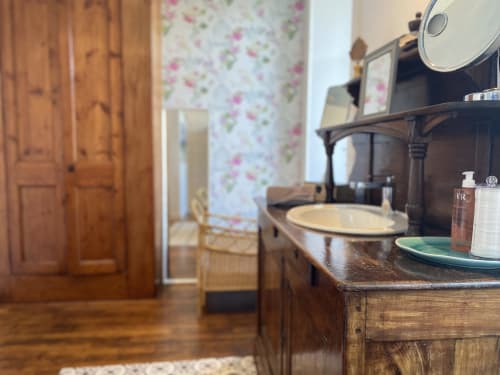 Vintage bedroom with wooden furniture, floral wallpaper, and sink at L'Ermitage B&B, Saint-Vaast-la-Hougue